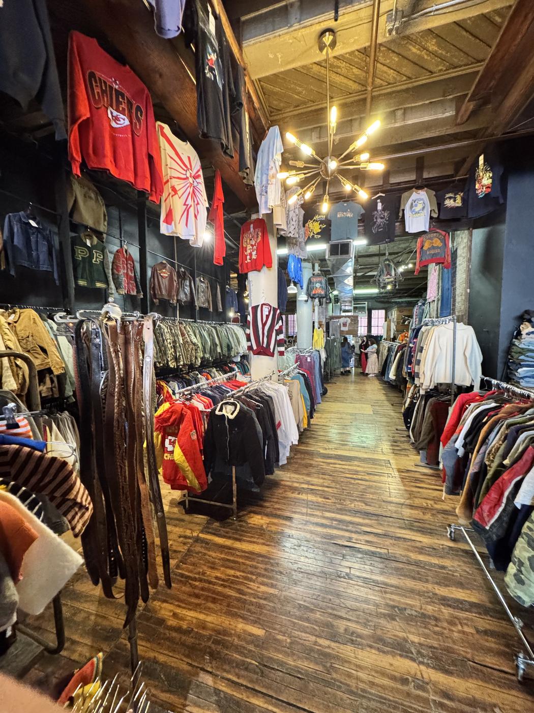 The aisle at 6 Foot Closet, looking down the room under a sputnik chandelier past varsity jackets